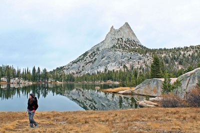 Hiker next to a lake with a mountain in the background