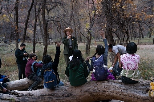 Two rangers lead a group of young students in an activity.