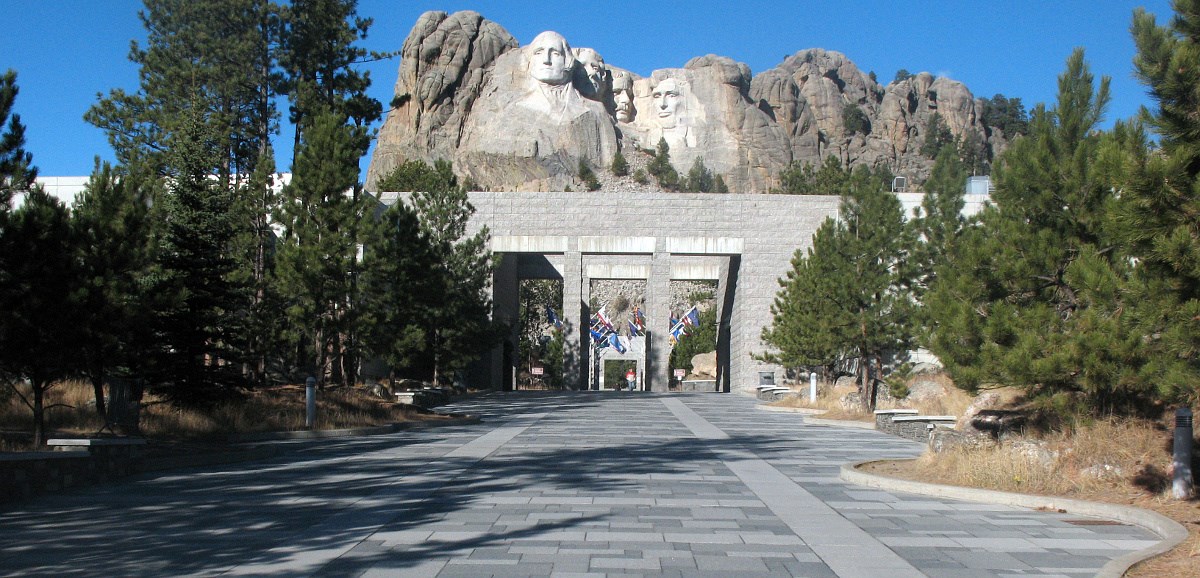 Stone walkway leading to stone arch with Mount Rushmore in background