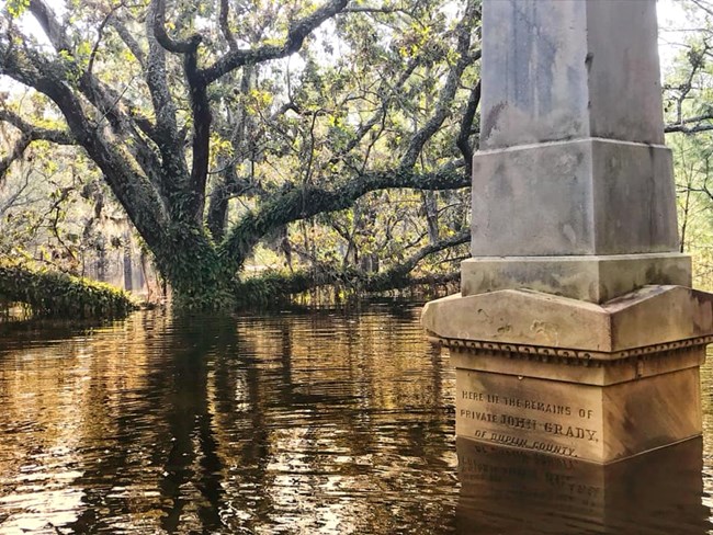 A battlefield monument and a tree are submerged in flood waters