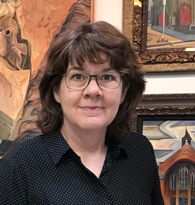 Photograph of artist Kathy Hodge with paintings in the background