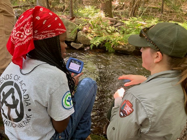 AYCC crew member and supervisor have a conversation next to a stream