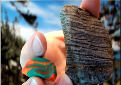 hand holding a rock with lines and playdoh made to look like the rock