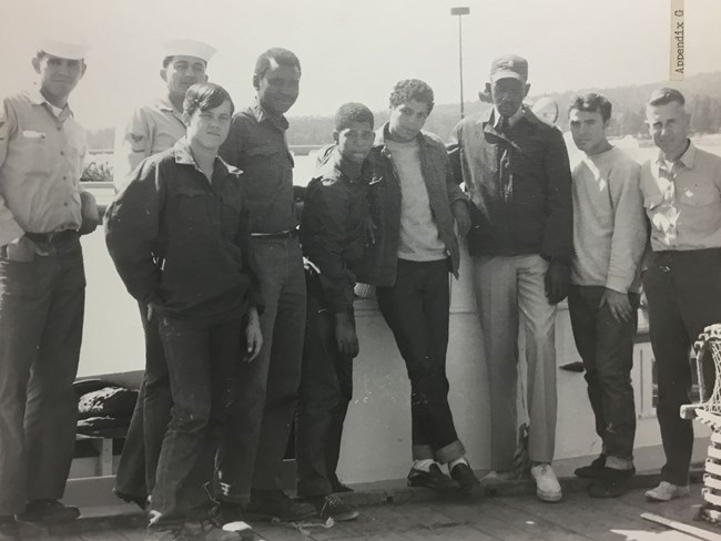 young men lean against a wall in front of a harbor