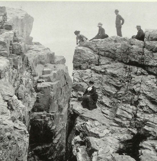 B&W photo of 19th century men and women on rocky cliff