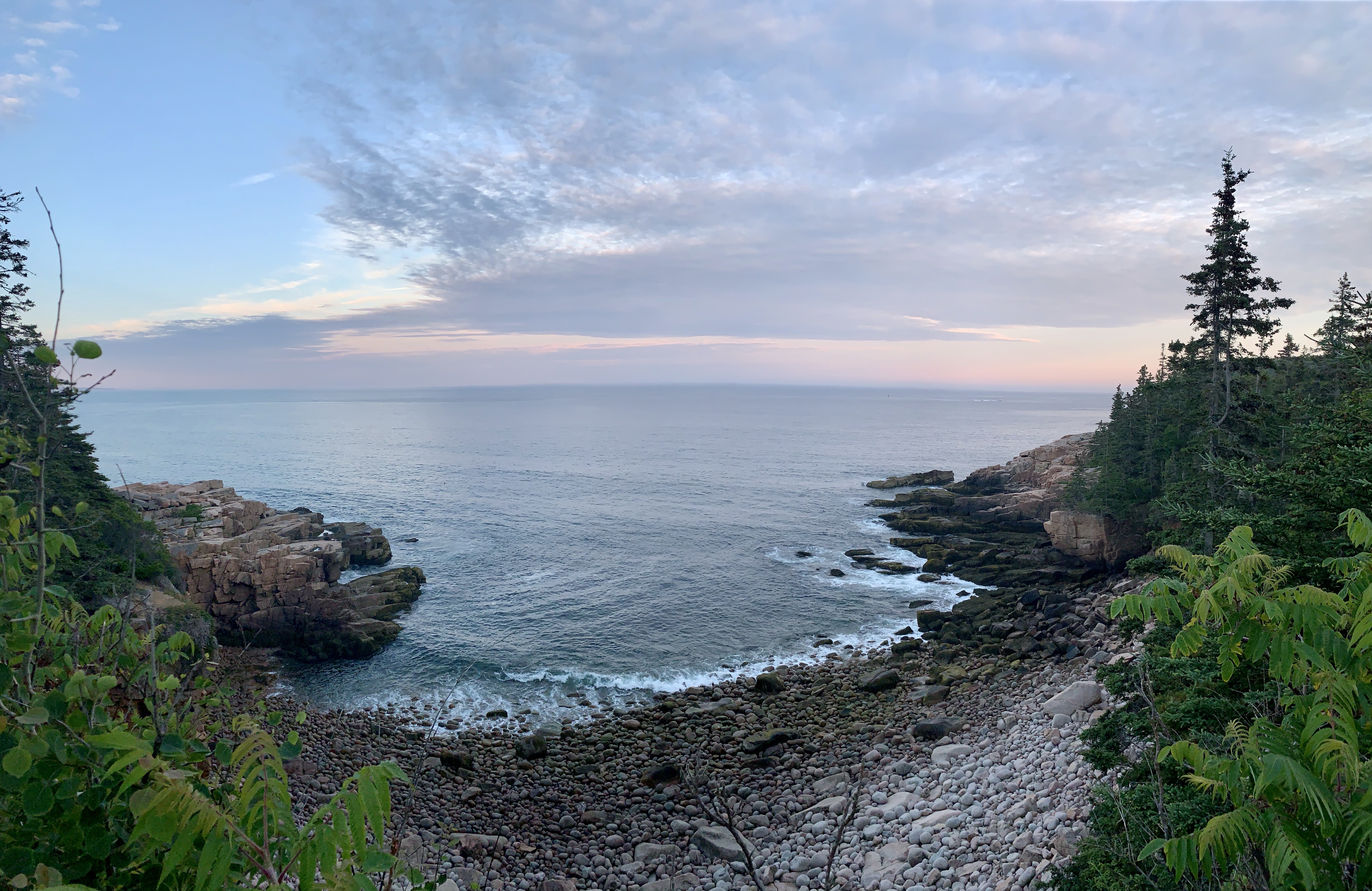 Waves crashing on shore of cobblestone beach at sunset