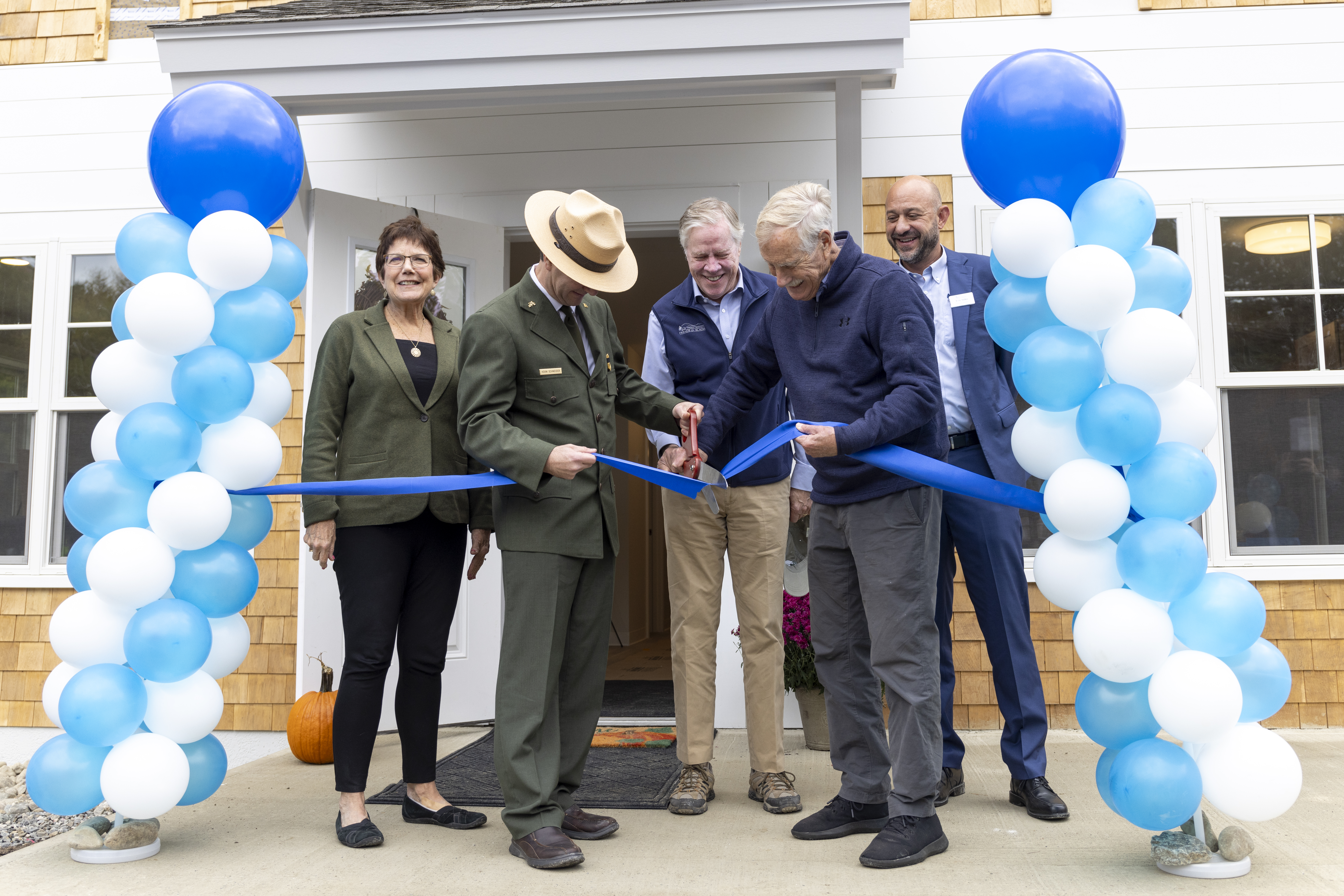 A group of five individuals, one in Ranger uniform, cut the ribbon to new park housing units in Acadia.