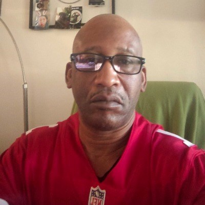 Bald African-American man in red jersey and glasses.