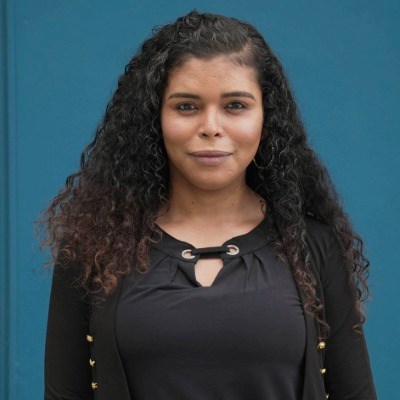 Woman with wavy brown hair and black shirt smiles at camera.