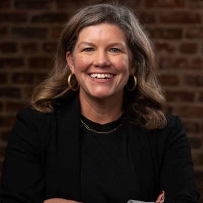 Blong woman in black blazer smiles at camera