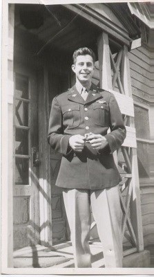 A man in uniform poses on a porch