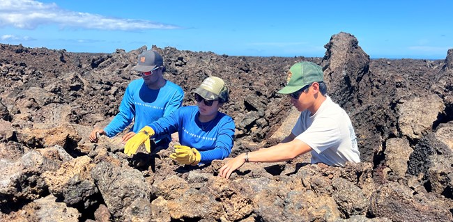 Group of young people stack rocks on trail