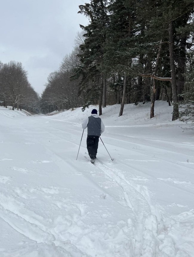 A man skiing on the railroad trace covered in snow.
