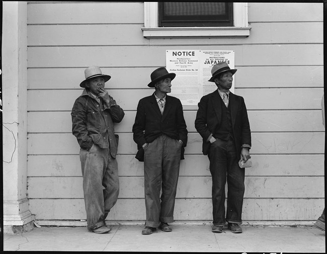 three men standing in front of a relocation notice sign