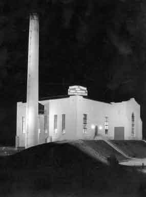 Black and white photograph taken at night with the tower and plant brightly lit.