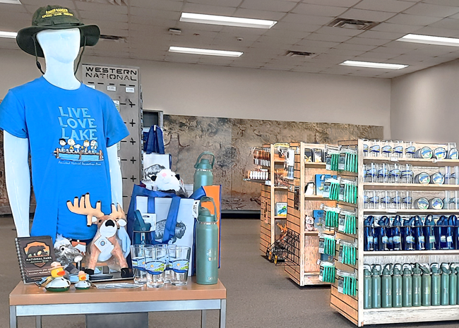 Three shelf units full of books, postcards, bandanas, patches, pins, stickers, and park passport book items for sale.