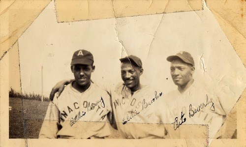 Three Black men in baseball uniforms look at the camera