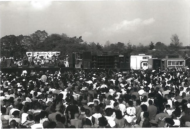 Thousands of people are around a stage in an open field