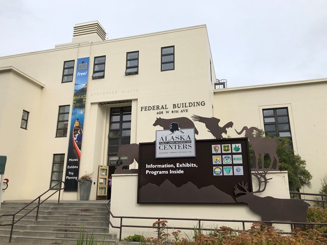 Large cream-colored building with sign and banner.