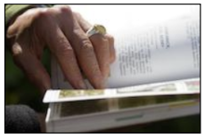 A hand leafs through a nature book.