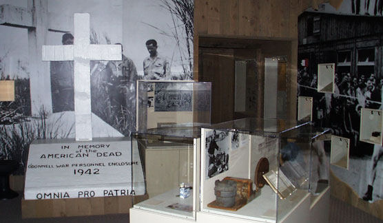 White cross monument in a room of museum exhibit cases