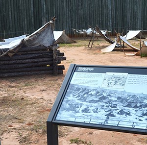Reconstructed prison corner with replica shelters and wayside exhibit panel