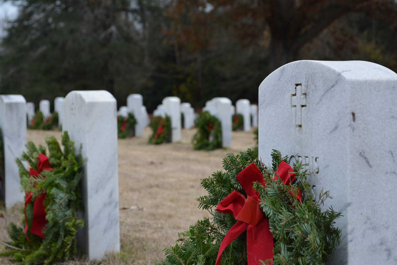 Headstones with decorative wreaths placed in front of them.