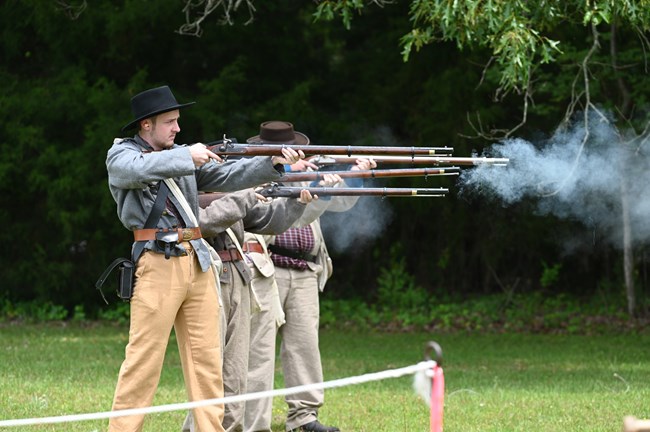 Living historians firing muskets during an infantry demonstration.