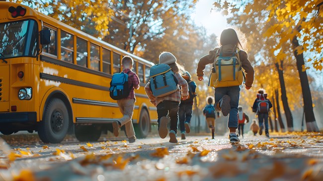 Yellow schoolbus with children running toward it