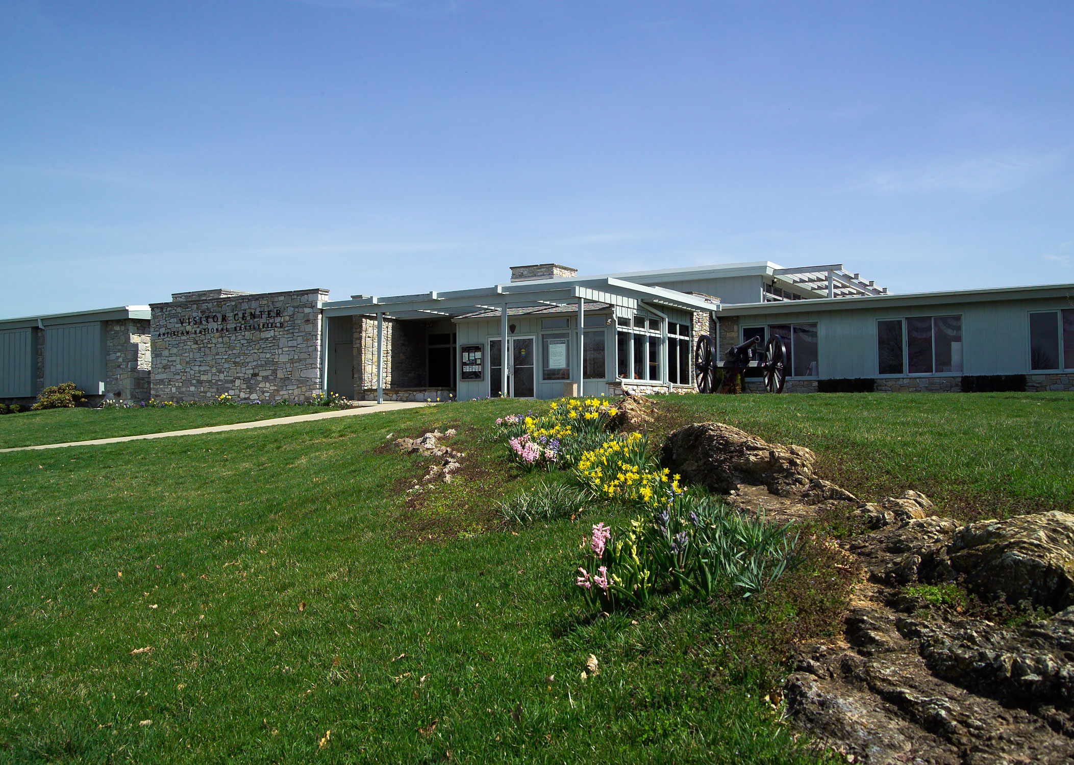 Antietam Visitor Center entrance with flowers growing on the ground nearby.