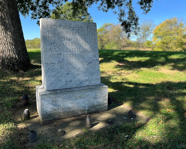short light gray stone with carved text in grass field