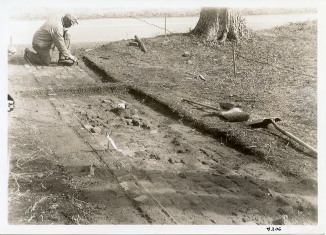 An African American man conducts archeology work uncovering a brick walkway