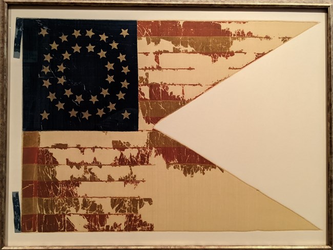 Guidon, pennant shaped flag, with red and white stripes with a circle of stars on a blue background.