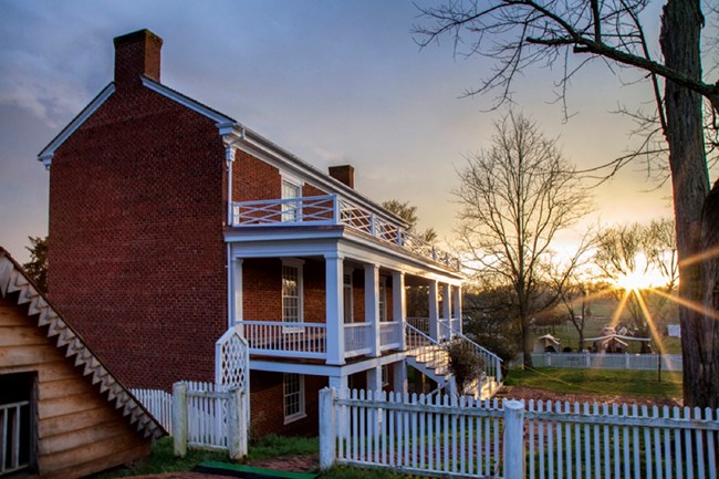 Brick house with steps going to the second floor with the sun setting in the background