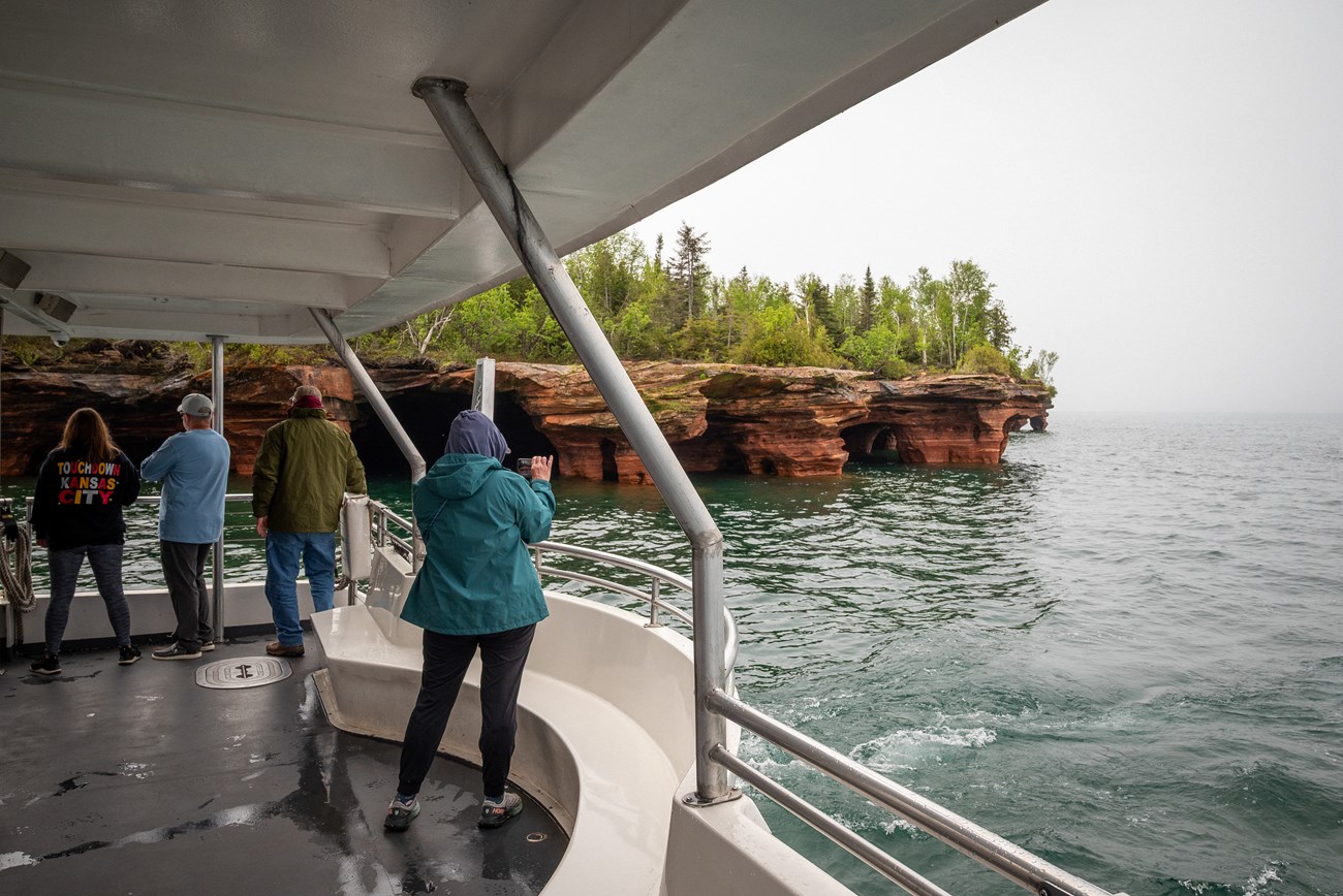 Photograph from stern of cruise boat with people looking out at the sandstone cliffs of Devil's Island.