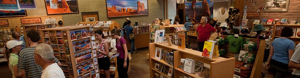 A busy bookstore with customers browsing shelves full of books, postcards, and other souvenirs.