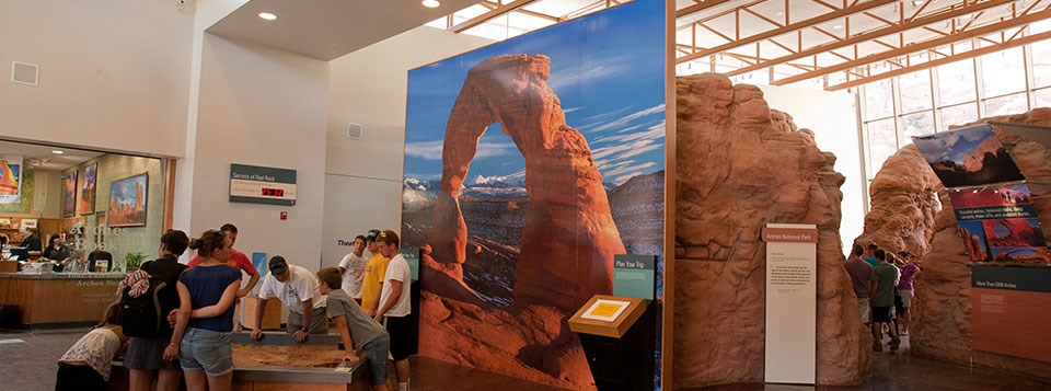 a large room with exhibits. a large photo of Delicate Arch covers a wall