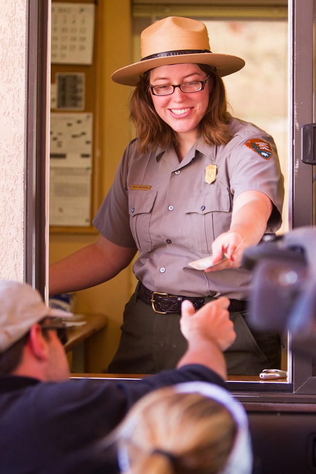 A smiling ranger welcomes a visitor to Arches in the entrance booth.