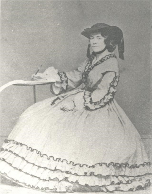 A woman in a hoop skirt writing on a pad of paper.