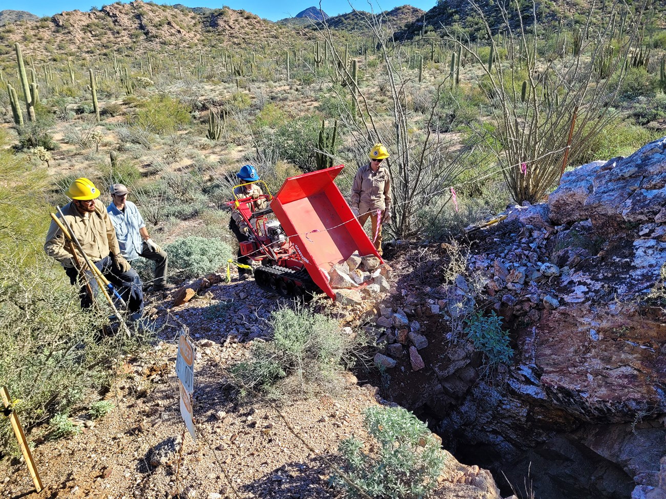 a group of people in hard hats use a machine to move rocks into an abandoned mine
