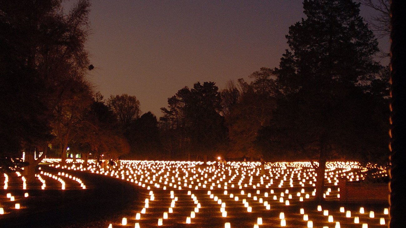 Thousands of luminaries light of the headstones of a cemetery.