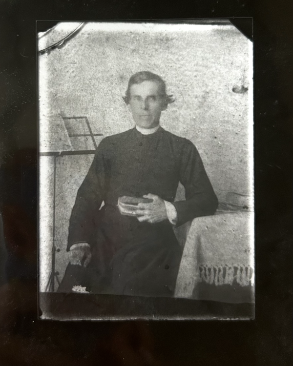 portrait of man sitting holding a bible and leaning on a table
