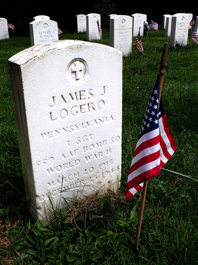 a circa WWII US-issued headstone, marked by an American flag.