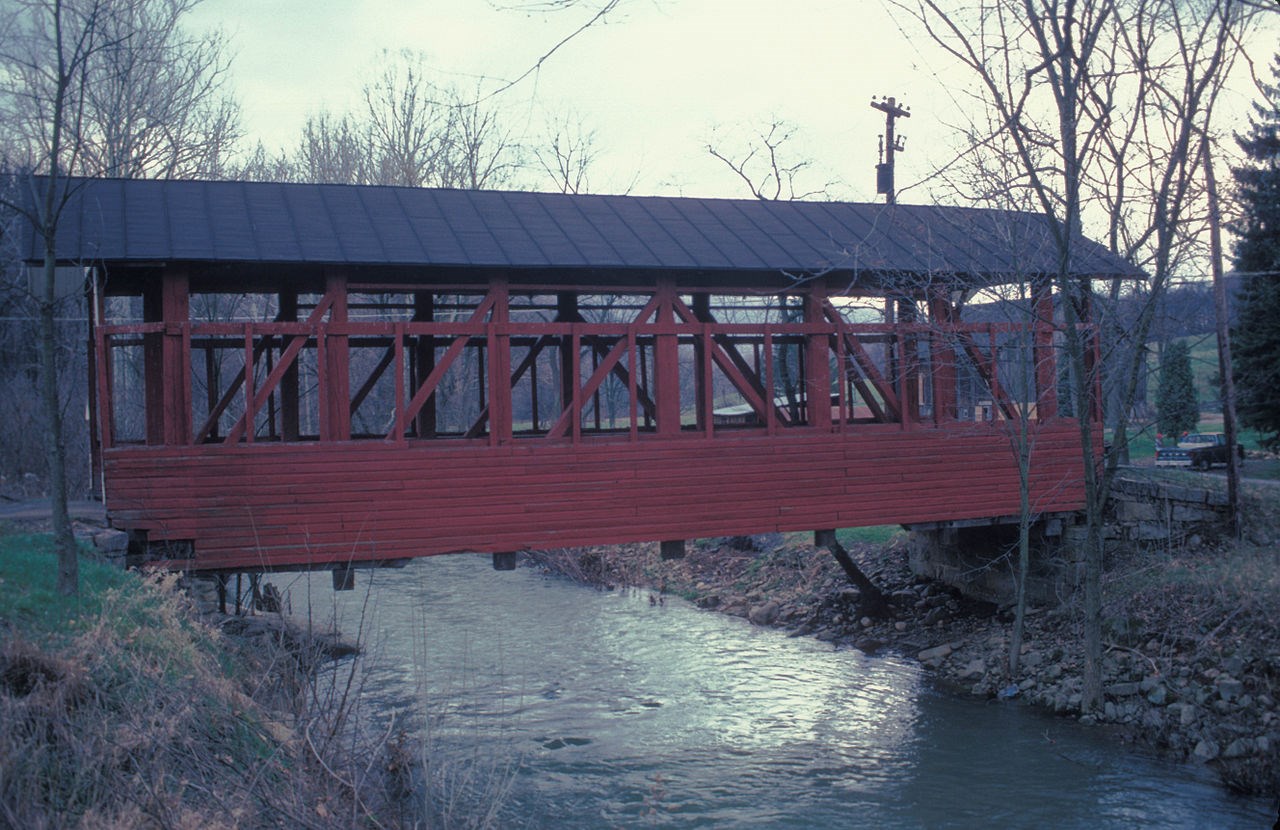 Red covered bridge over a body of water.
