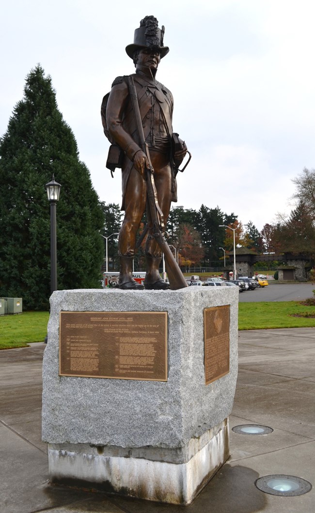 A life-size bronze statue of John Ordway stands on top of a square granite base on which are attached two bronze plaques.  Ordway’s rifle is resting in front of him and he is wearing his military uniform with a tall military hat.