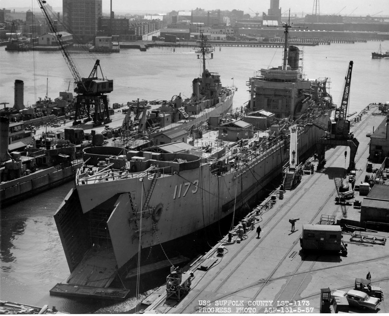 USS Suffolk County docked alongside a pier and under construction.