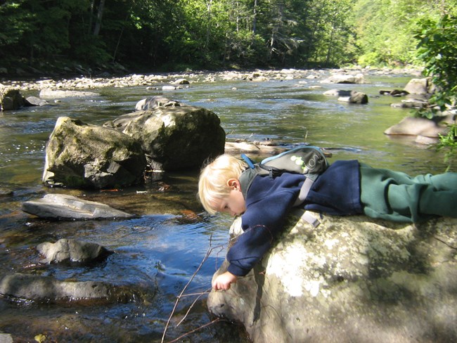 Child looking into reflection in the river