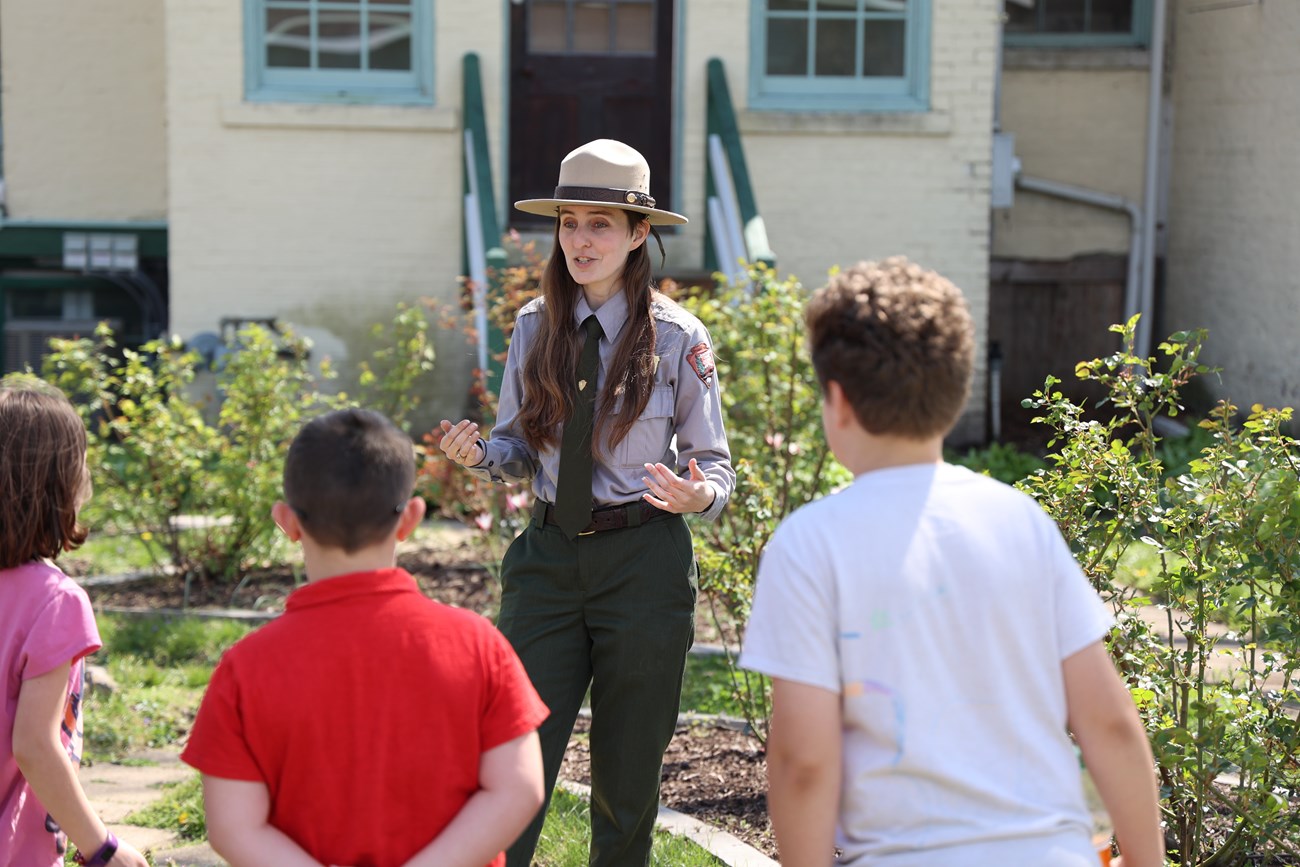 Ranger gives talk to three visitors in a garden on a sunny day