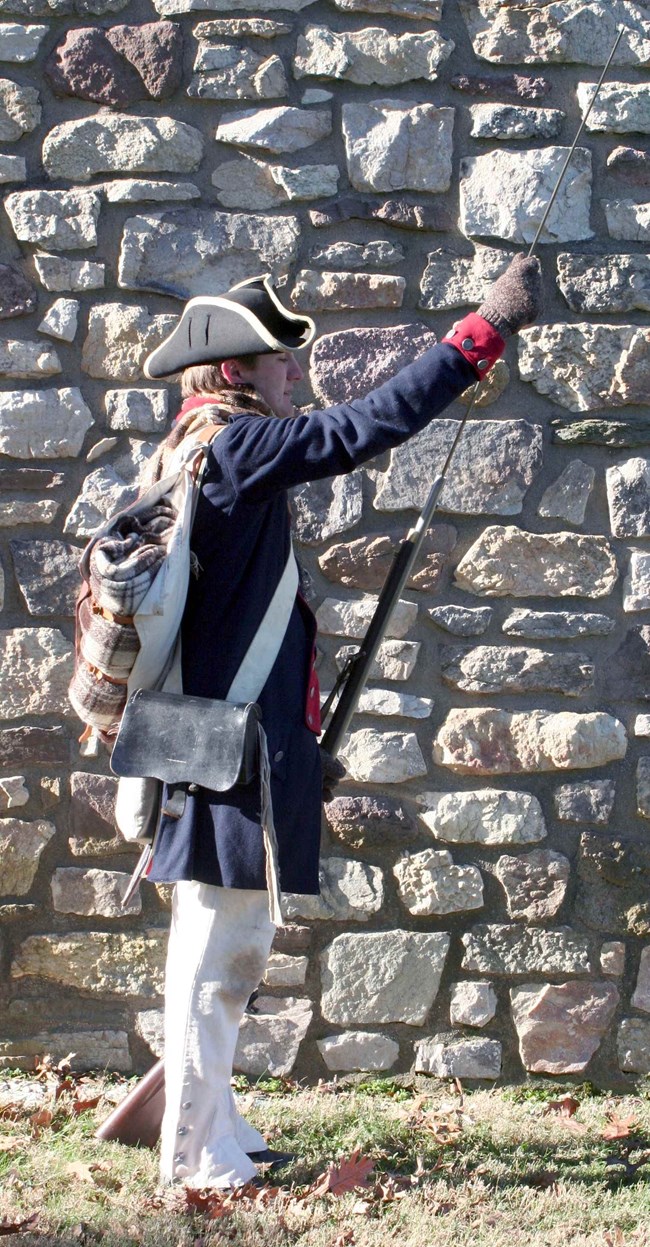 Continental Army soldier drills, using a ramrod to muzzle load a cartridge into a musket.