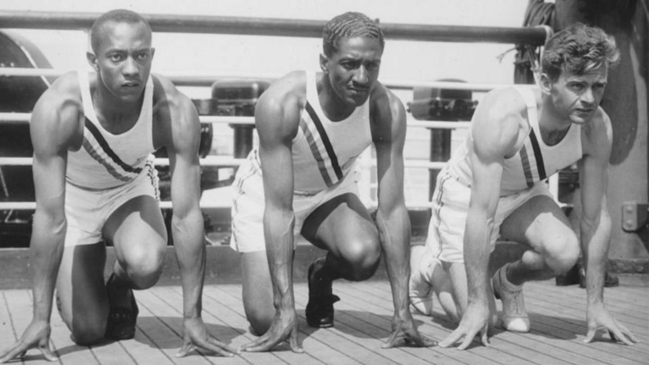 Three Olympic athletes crouched down, prepared to have a foot race.